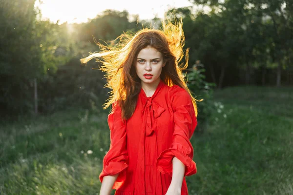 Attraktiv kvinna i röd klänning poserar i naturen grönt gräs — Stockfoto