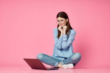 Pembe arka planda dizüstü bilgisayarı olan kadın çevrimiçi alışveriş eğlencesi