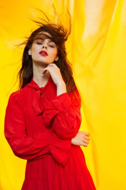 Kırmızı elbiseli güzel kadın. Arka planda doğa sarısı kumaş.