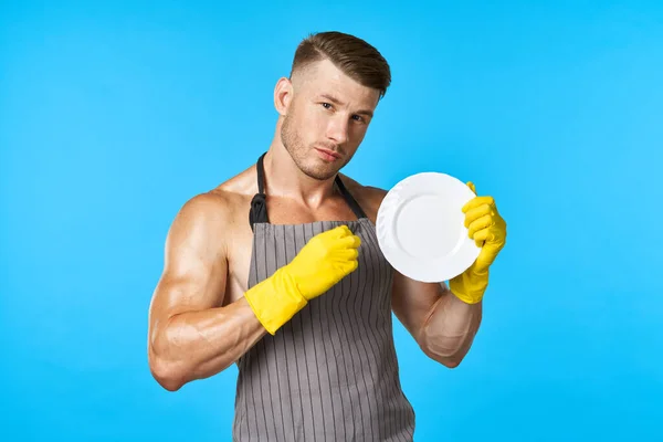Dishwasher rubber gloves plate in hands blue background — Stock Photo, Image