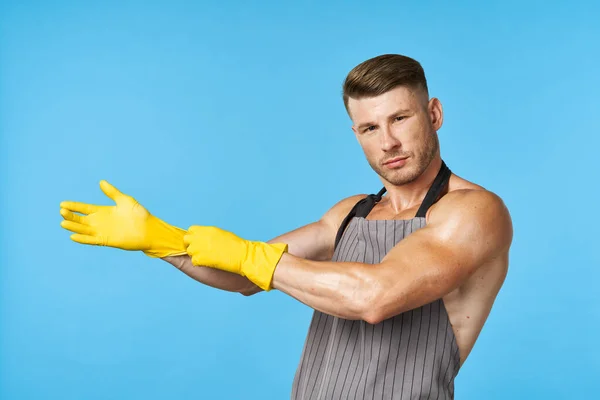 Man in schort met opgepompt lichaam rubber handschoenen schoonmaken blauwe achtergrond — Stockfoto