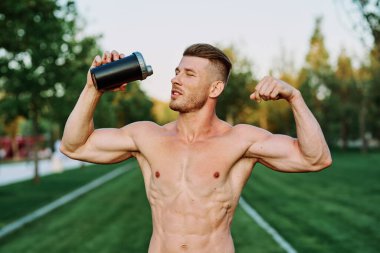 Parktaki egzersiz motivasyonunda kaslı vücutlu atletik bir adam.