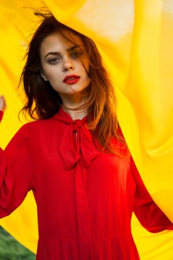 Kırmızı elbiseli güzel kadın. Arka planda doğa sarısı kumaş.