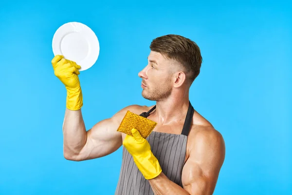 Человек в фартуке чистки посуды синий фон — стоковое фото