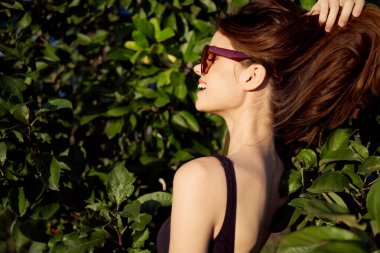 Güneş gözlüğü takan çekici kadın yaz mevsiminde tropik doğaya poz veriyor.