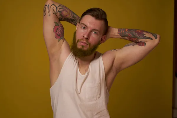 Macho man in white t-shirt tattoos on his arms posing isolated background — Stock Photo, Image