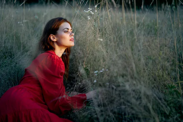 Woman in the field lies on the grass in a red dress posing — Stock Photo, Image
