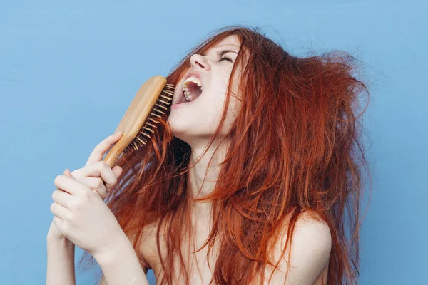 Mulher com cabelo vermelho pente cuidado azul fundo — Fotografia de Stock