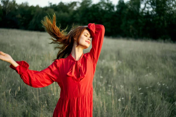 美しい女性の赤いドレスでフィールド自然ポーズ風景 — ストック写真
