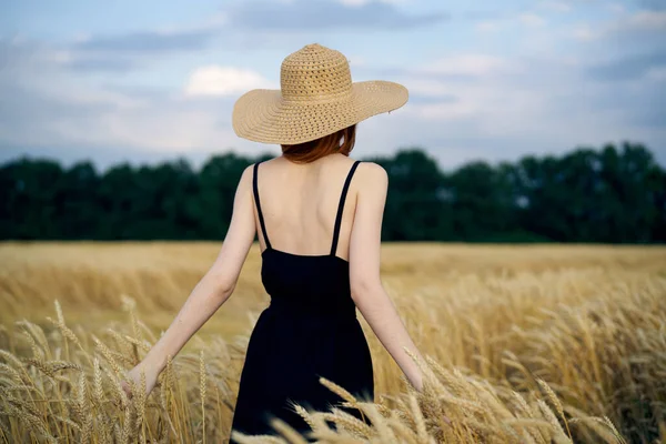 Femme en robe noire marchant dans le champ air frais — Photo