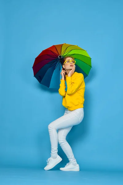 Frau mit buntem Regenschirm in gelbem Pullover posiert in Regenbogenfarben — Stockfoto