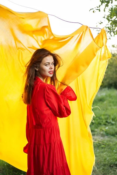Kvinnor nära gult tyg i naturen i röd klänning mode — Stockfoto