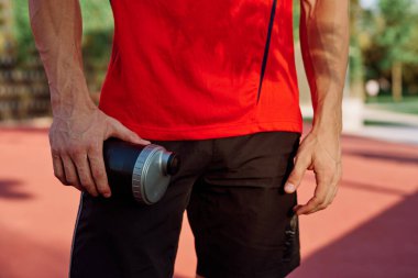 Sportif adam parkta dinleniyor, bankta atıştırıyor.
