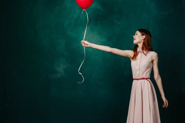 Kırmızı balonlu kadın yeşil arka planda tatil eğlencesi