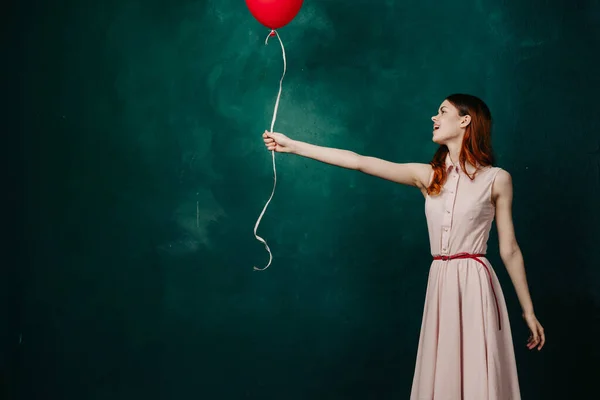 Žena s červeným balónem na zeleném pozadí dovolená zábava — Stock fotografie