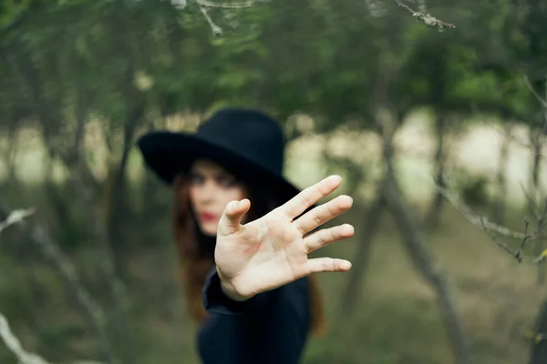 Nő egy fekete kalapban gesztikulál kezével boszorkány mágia fantázia — Stock Fotó