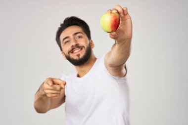 Beyaz tişörtlü sakallı adam, elma sağlığına uygun beslenme.