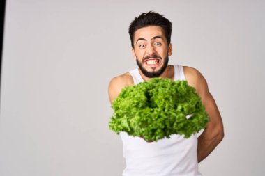 Beyaz tişörtlü neşeli adam marul sağlıklı yemek bırakıyor.