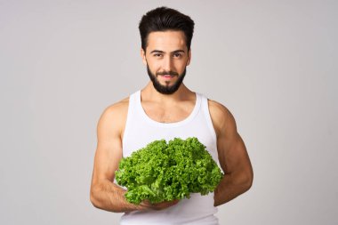 Beyaz tişörtlü neşeli adam marul sağlıklı yemek bırakıyor.