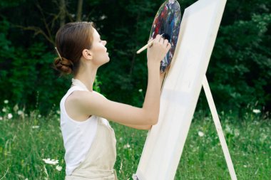 Kadın sanatçı doğa palet tablosu çizer yaratıcı manzara