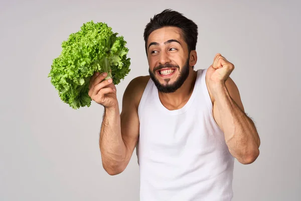 Homem alegre em uma alface de t-shirt branca deixa comida saudável — Fotografia de Stock