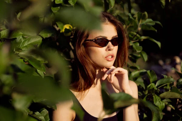Bonita mulher vestindo óculos de sol folhas verdes posando verão — Fotografia de Stock