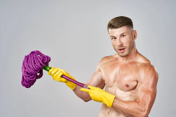 黄色い手袋をした男が手にモップを持って掃除してる — ストック写真