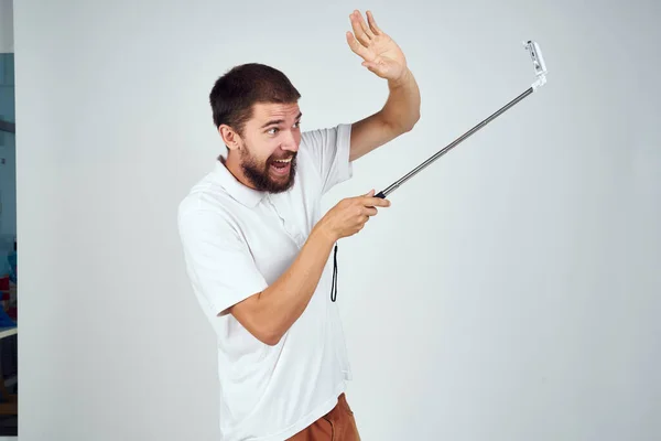 Vousatý muž v bílém tričku selfie stick photo technology — Stock fotografie