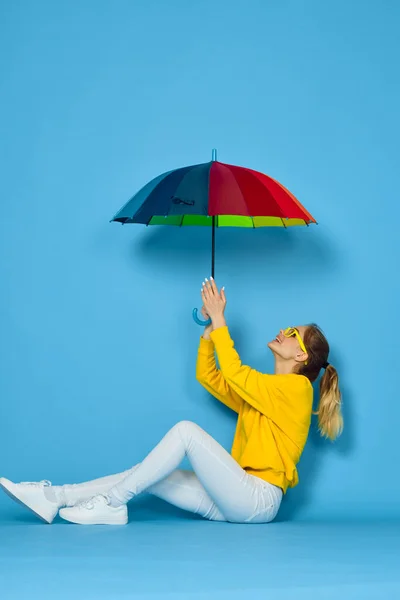 黄色のセーターに多色の傘を持つ女性が虹色をポーズ — ストック写真