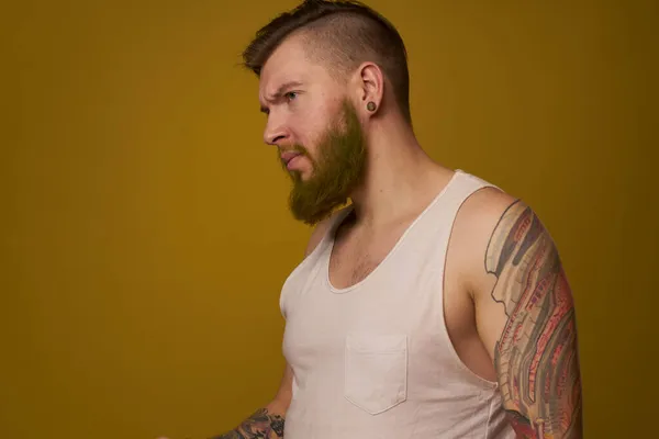 Macho hombre en blanco camiseta tatuajes en sus brazos posando aislado fondo — Foto de Stock