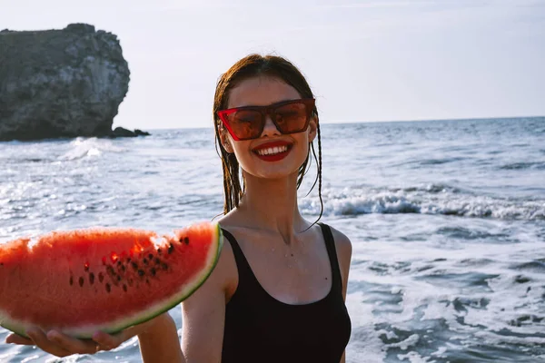 Ellerinde karpuz olan siyah mayo giymiş güzel bir kadın.