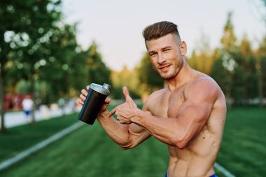 Parktaki egzersiz motivasyonunda kaslı vücutlu atletik bir adam.