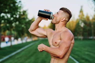 Parktaki egzersiz motivasyonunda kaslı vücutlu atletik bir adam.