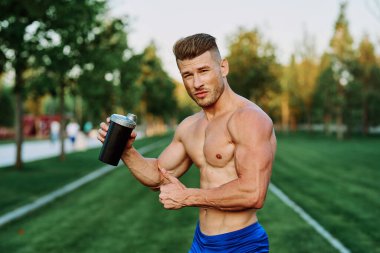 Parktaki egzersiz motivasyonunda kaslı vücutlu atletik bir adam.