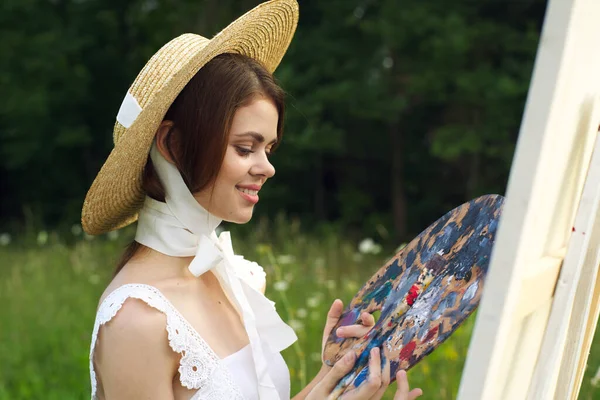Bella donna in cappello artista dipinge un quadro sulla pittura natura — Foto Stock