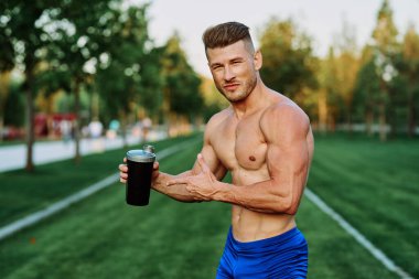 Parktaki egzersiz motivasyonunda kaslı vücutlu atletik bir adam.