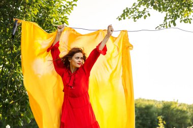 Elleri sarı kumaşlı, kırmızı elbiseli kadın.