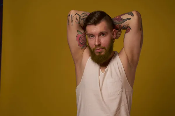 Macho hombre en blanco camiseta tatuajes en sus brazos posando aislado fondo — Foto de Stock