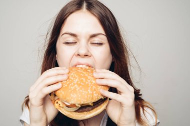 Elinde hamburger olan bir kadın. Atıştırmalık bir fast food.