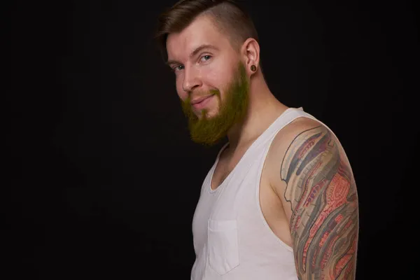 Man met baard in wit t-shirt met tatoeages op zijn armen poserende bullebak — Stockfoto