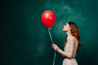 Kırmızı balonlu neşeli kadın yeşil arka plan tatili