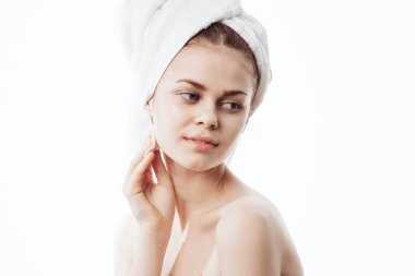Kafasında beyaz havlu olan neşeli bir kadın. Yüz kremi sürmüş.