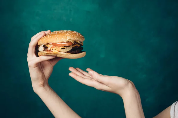 Hamburger w rękach zbliżenie fast food zielone tło — Zdjęcie stockowe