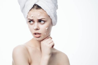 Kafasında beyaz havlu olan neşeli bir kadın. Yüz kremi sürmüş.
