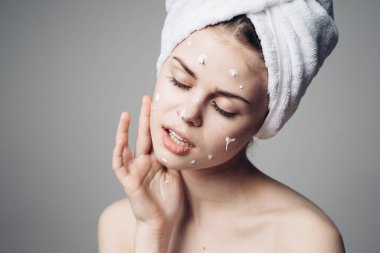 Çıplak omuzlu kadın yüz kremi sürmüş.