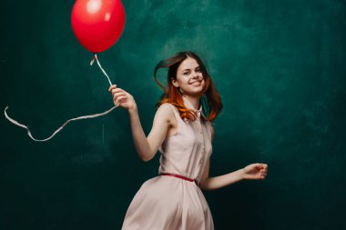 Kırmızı balonlu neşeli kadın yeşil arka plan tatili
