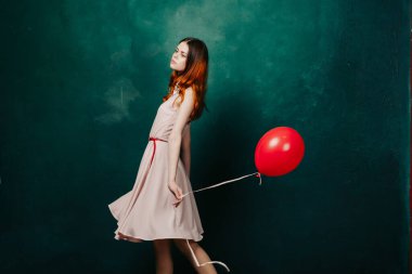 Kırmızı balonlu kadın yeşil arka planda tatil eğlencesi