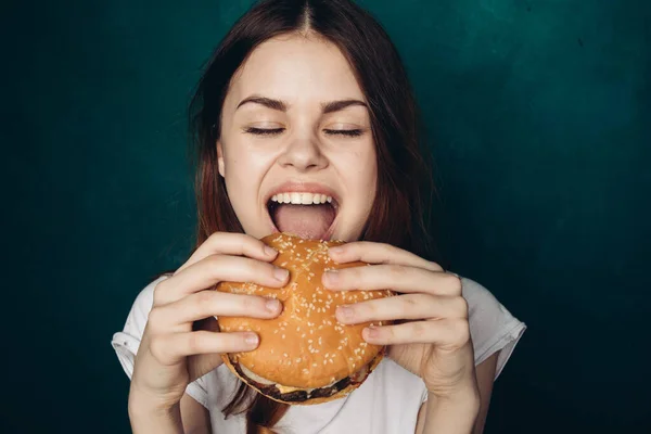 Femme gaie avec hamburger près du visage grignotage restauration rapide — Photo