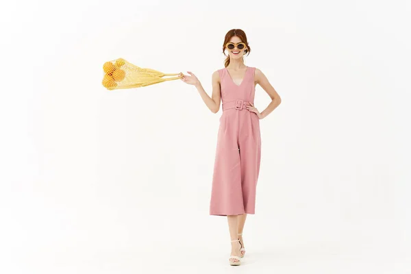 Mulher em um vestido rosa e com um pacote de laranjas — Fotografia de Stock