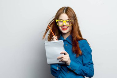 Not defteri ve kalem takan, sarı gözlüklü profesyonel bir iş kadını.